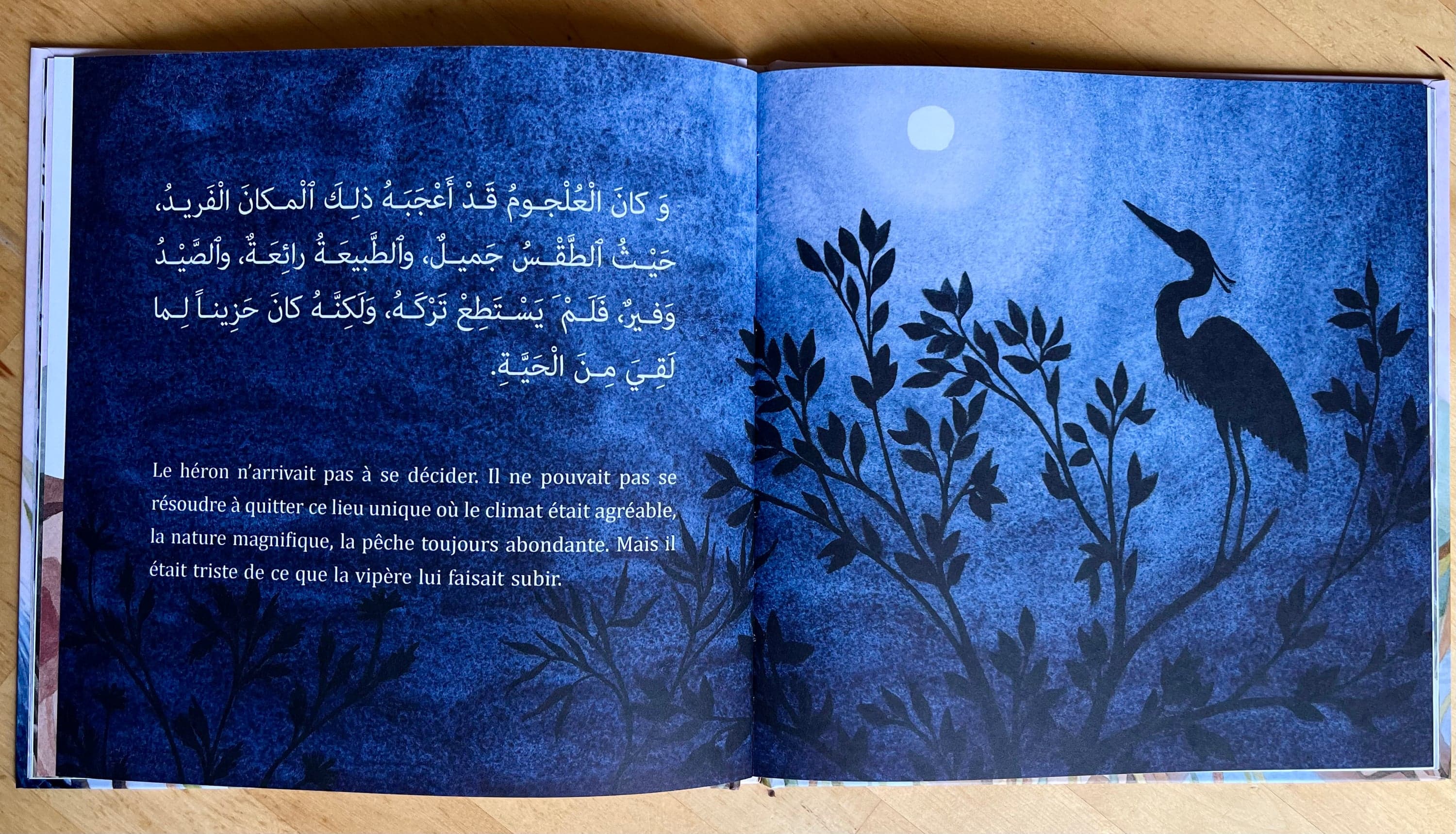 Illustration of Luna Olivier, from her project Le héron et la vipère. A photography of a double-page showing the heron silhouetted at night, with the French and Arabic text.